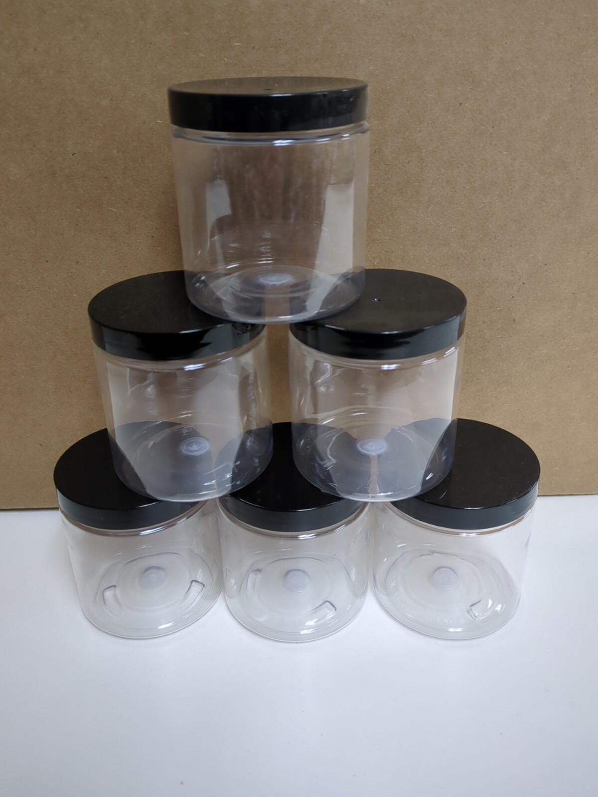 Six 8 oz clear plastic jars with black lids